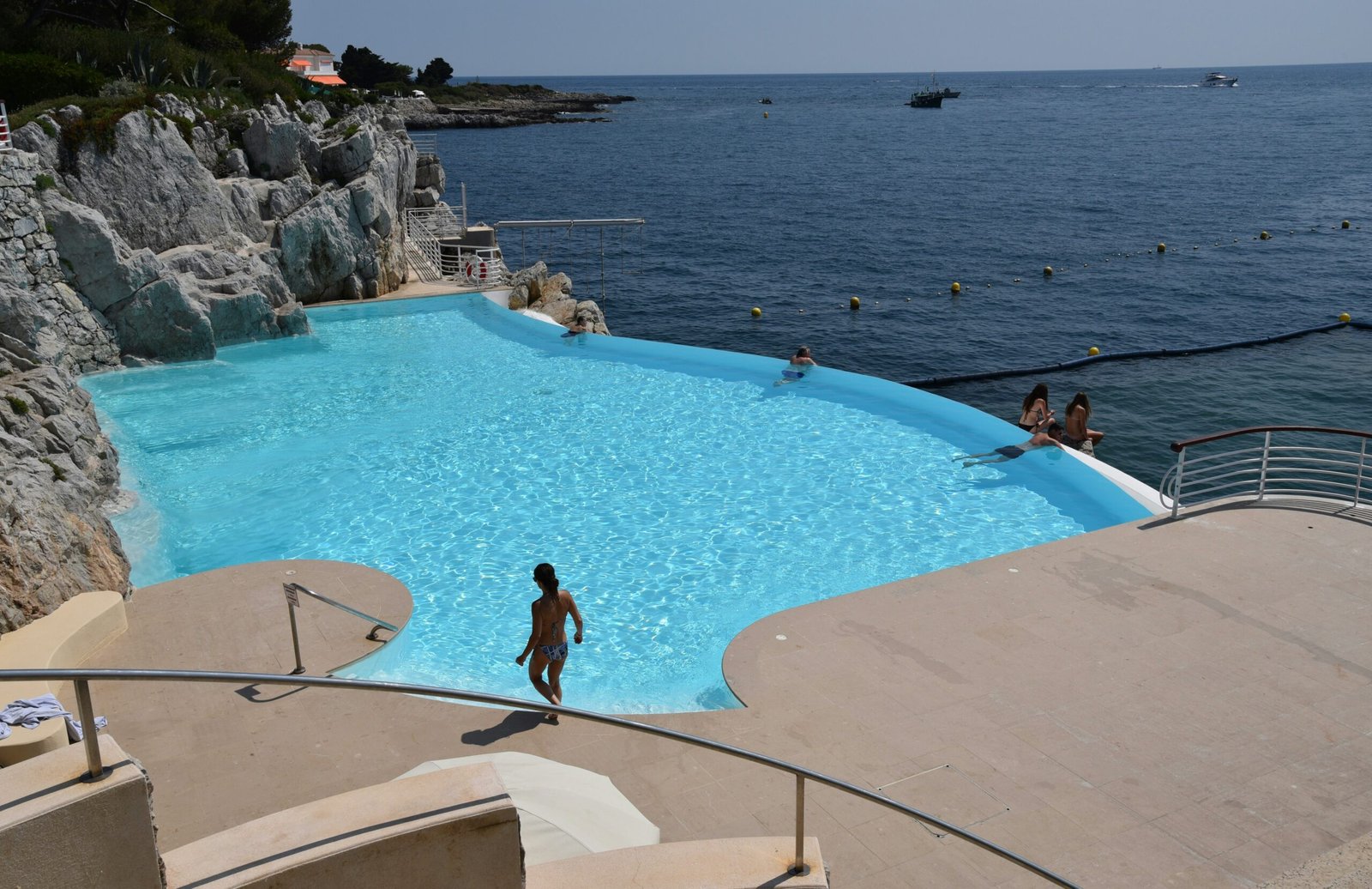 a person standing in a pool next to the ocean